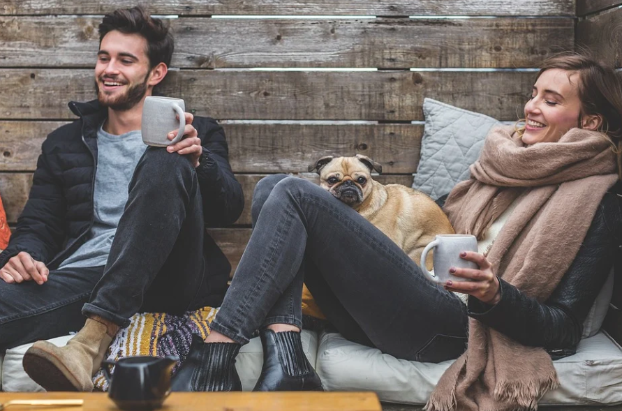 man and woman smile with a dog