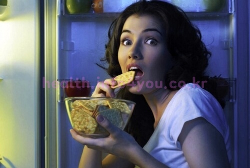 한밤중에 냉장고에서 음식을 꺼내 먹고 있는 여성