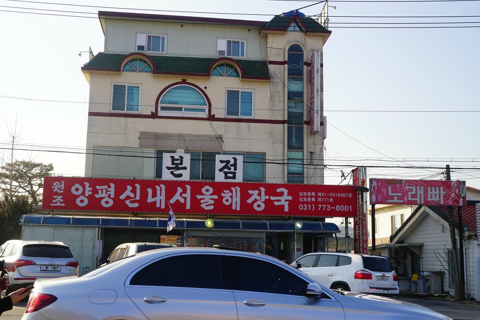 신내 서울해장국 본점 간판&#44; 빨간 바탕에 큰 흰 글씨. 그 옆에 노래빠&#44; 뒤로는 3층 건물