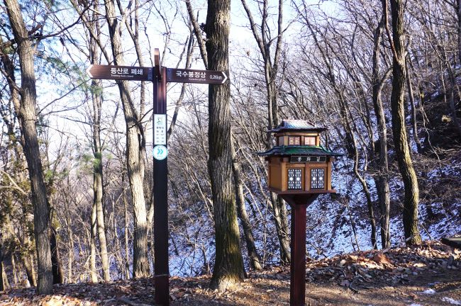 2층 정자형의 스탬프 함&#44; 왼쪽에 이정표&#44; 정상까지 260m&#44; 뒤로는 우거진 숲&#44; 응달진 산바탈에 녹지 않은 눈&#44;