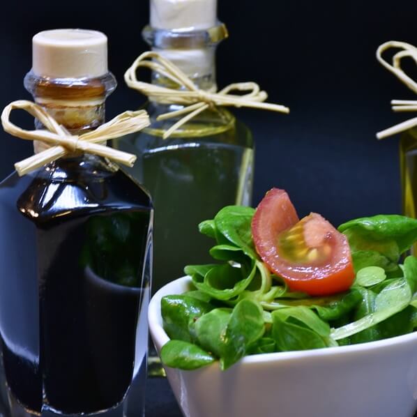 액상으로-된-식재료가-담긴-병-두-개와-토마토와-푸른-잎채소로-된-샐러드