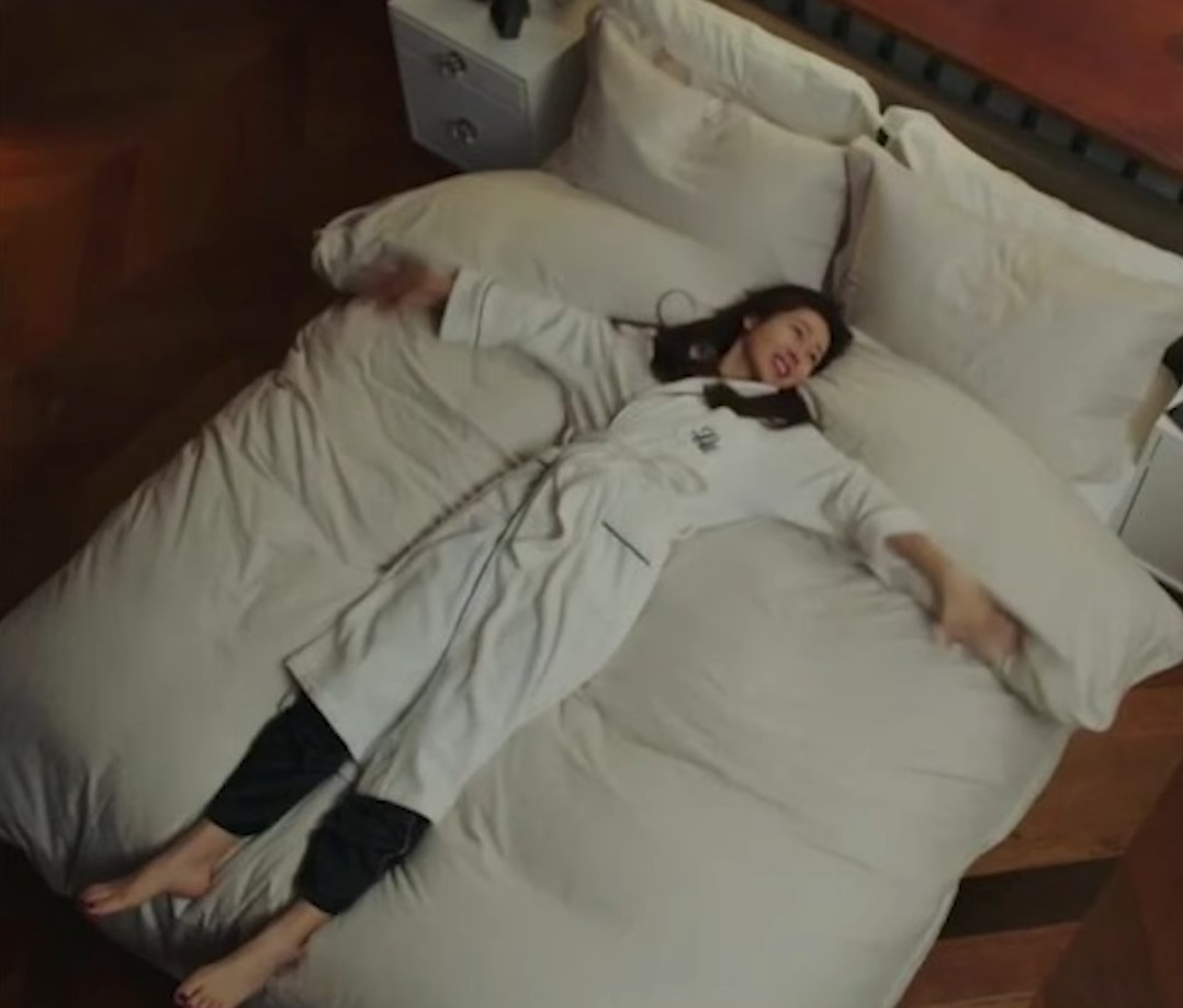 침대 누워보기 전문가인 여성이 침대에 두 팔을 벌리고 대자로 누워있다.