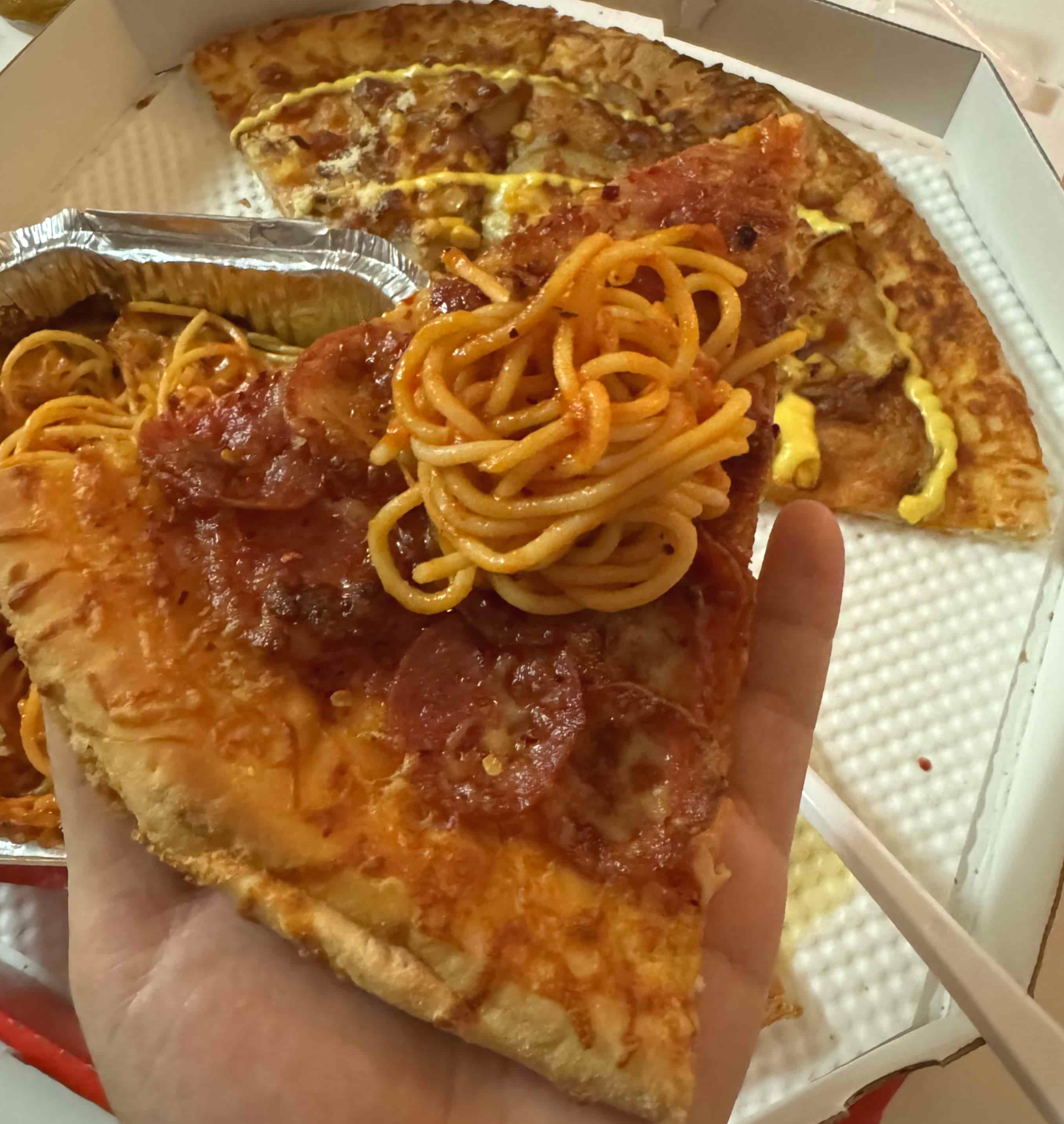 페퍼로니 피자 위에 토마토 치즈 스파게티를 올려서 먹는 사진이다.