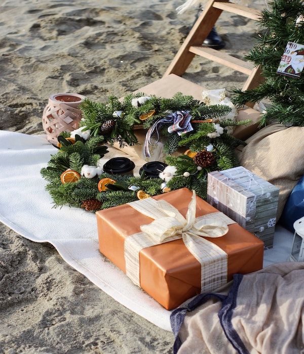 해변에서-성탄절을-축하하는-소나무줄기다발과-선물박스가-있는사진