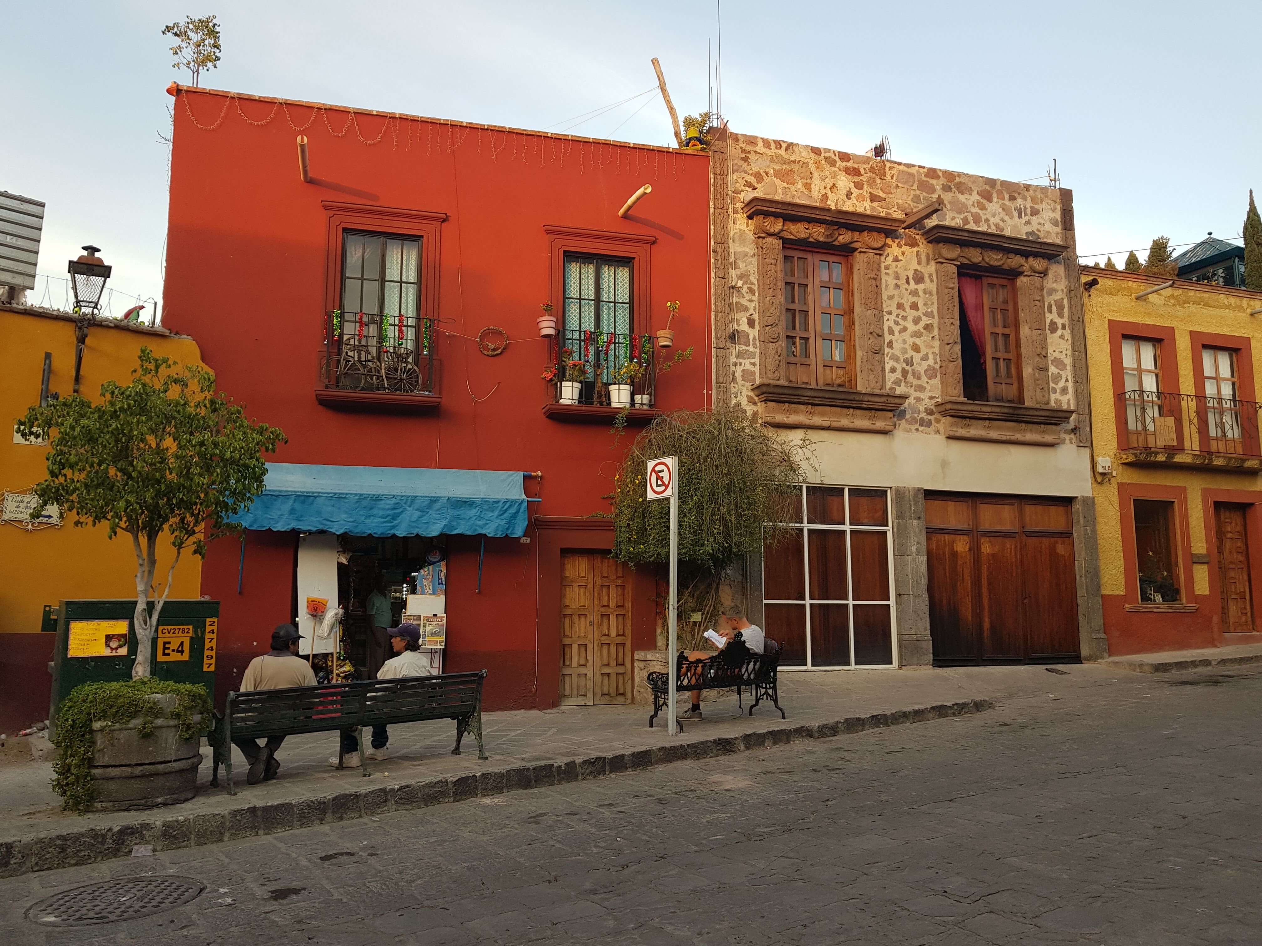 멕시코산미겔의 마을모습 빨간 하얀 노란 작은 2층짜리의 건물들이 늘어서 아기자기한 마을의 모습 벤치에 사람들이 여유를 부리고 있는 모습