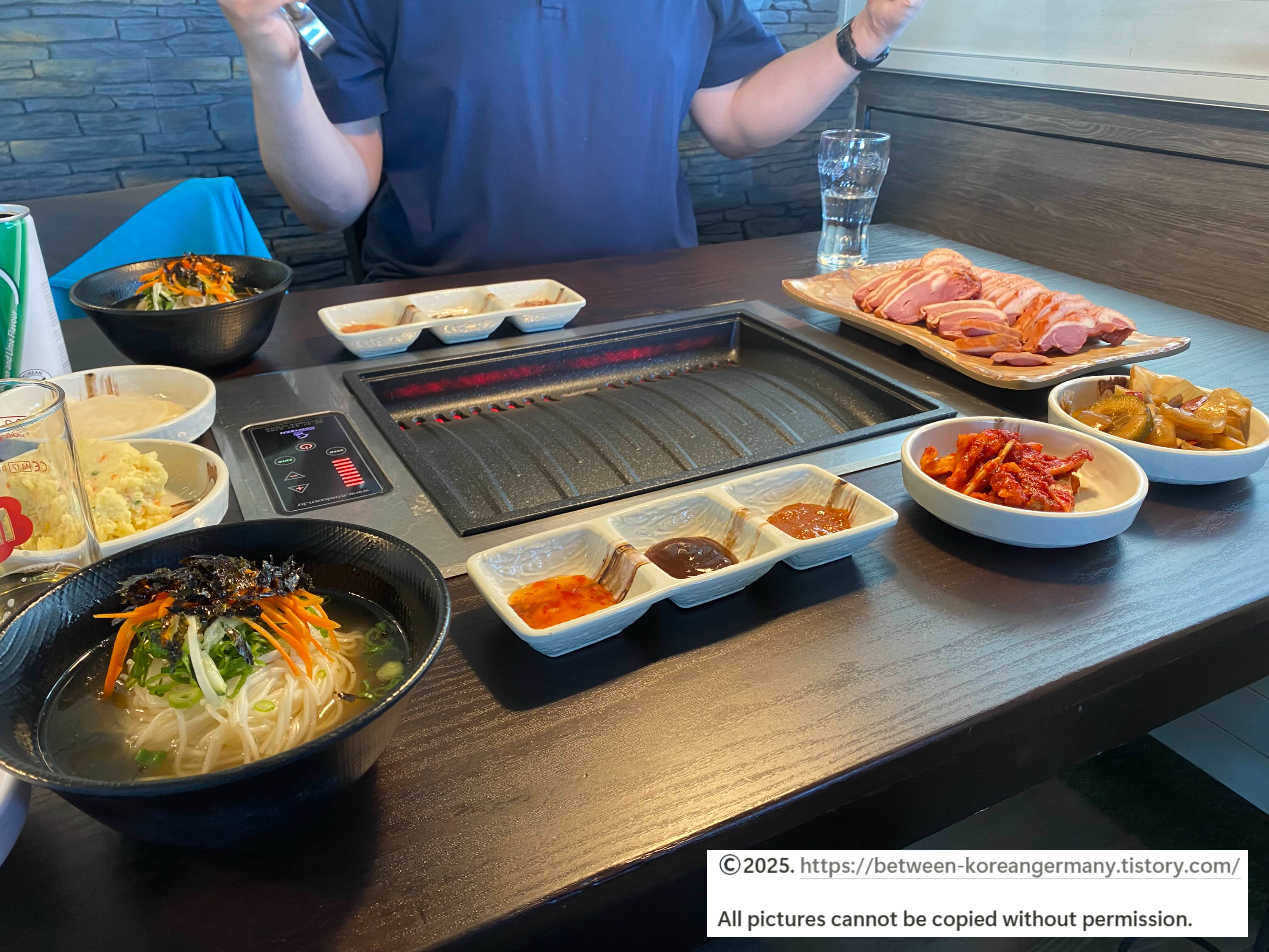 검정색-불판-옆에-놓여-있는-구워지지-않은-생고기와-밑반찬
