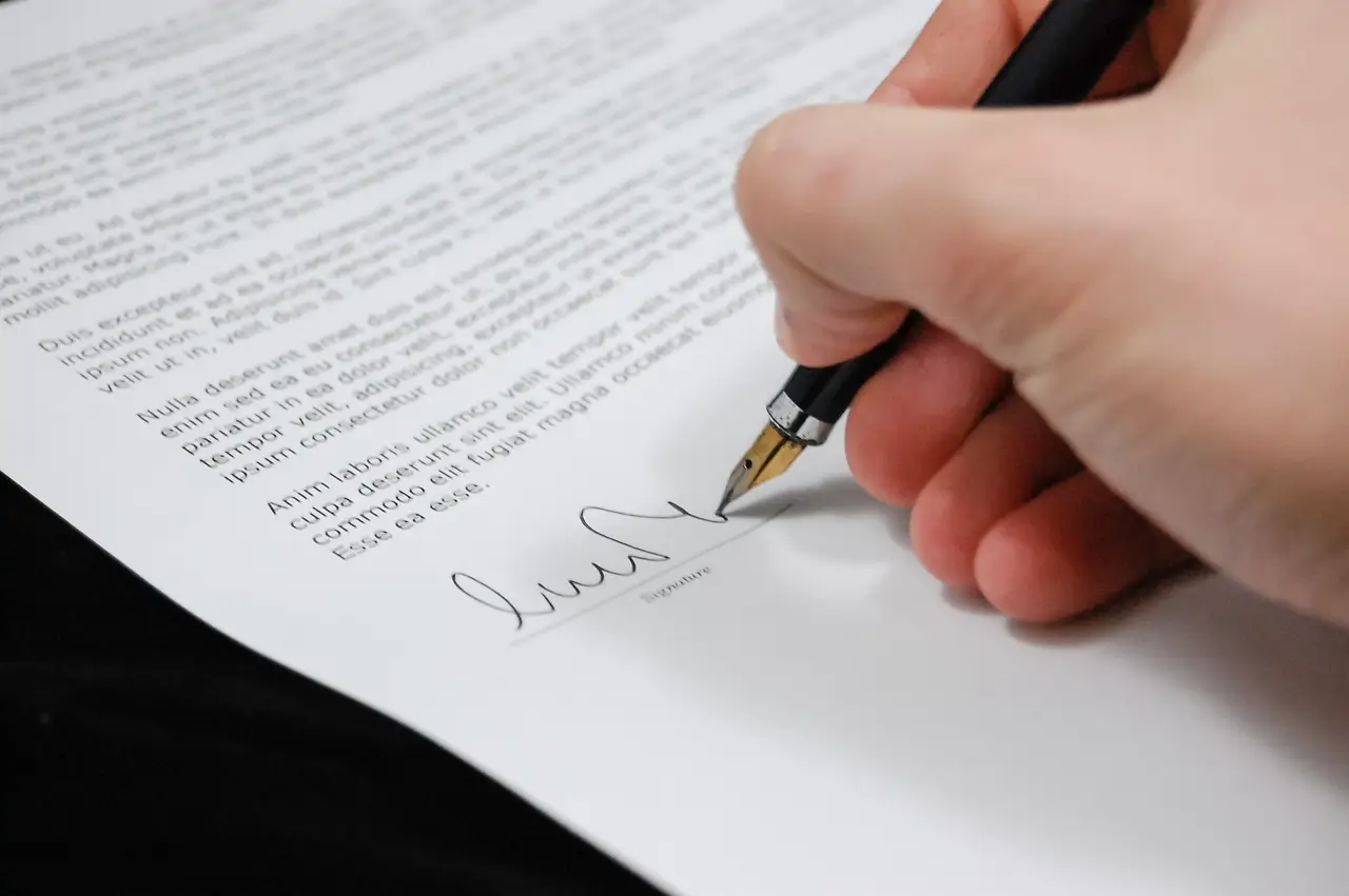 교통사고-검은바닥 흰종이 위 검은 글씨 아래 펜을 든 오른손이 서명하는 이미지