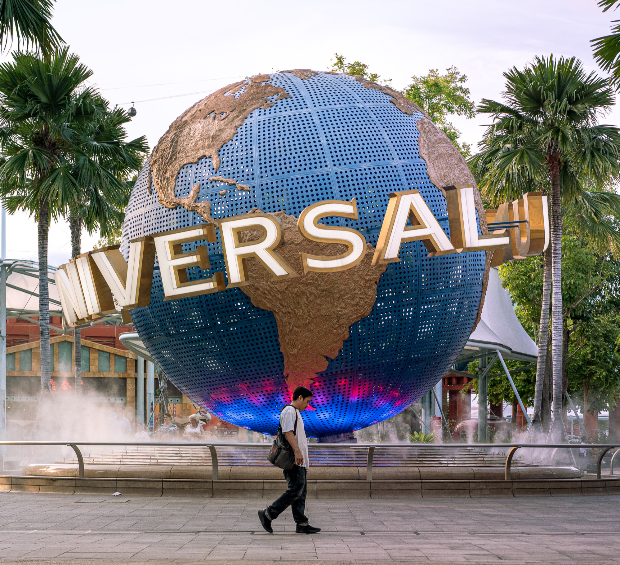 싱가포르 유니버설 스튜디오의 상징인 지구본과 그 앞을 지나가는 한 남자의 모습