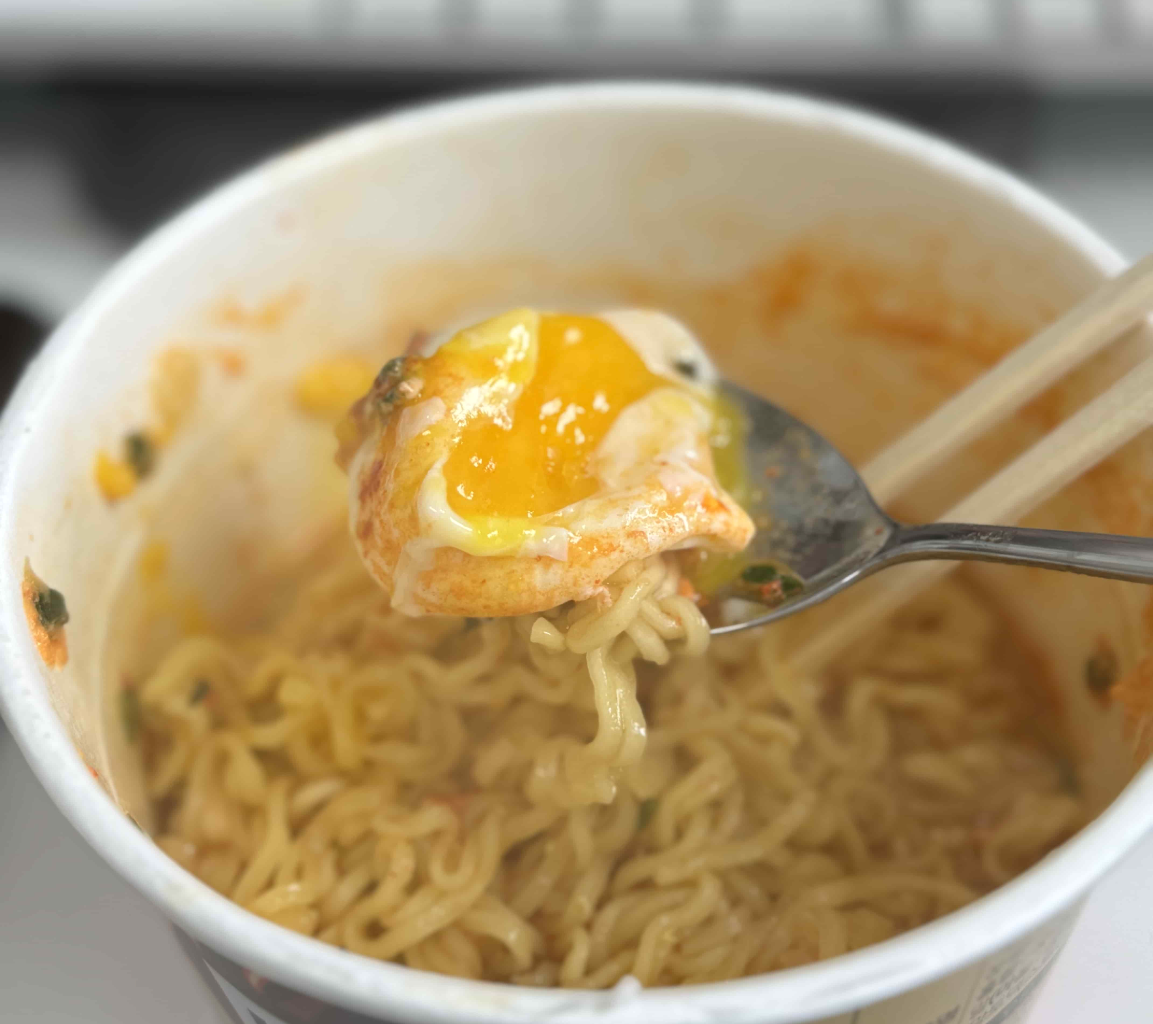 라면에 넣은 계란을 숟가락으로 먹는 사진