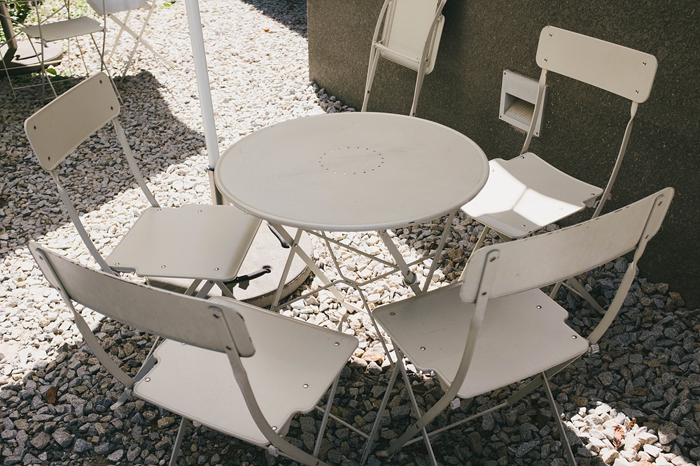 흰 둥근 철제 테이블과 테이블을 둘러써고 있는 흰 철제 의자 4개.