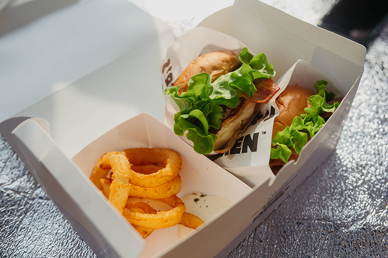 양양 파머스 키친 햄버거. 햄버거 두 개와 어니언링이 포장 상자에 담겨있다.