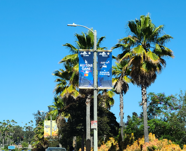 다저 스타디움으로 가는 길에 보이는 2022 올스타 게임 광고. 도로 가로등에 양쪽으로 파란색의 작은 현수막이 걸려 있다. LA All Star Game이란 글씨와 올스타 게임의 날짜&amp;#44; 장소가 적혀 있다. 