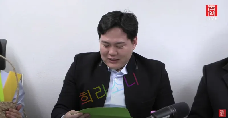 검은색 정장을 입고 머리를 단정히 정리한 23기 상철이 초록색 카드를 바라보며 고개를 숙이고 있다. 앞에는 검은색 마이크와 물병이 놓여 있으며, 화면 오른쪽 상단에는 '곤솔 LIVE' 로고가 보인다. 자막은 '희라소니'라고 적혀 있다.