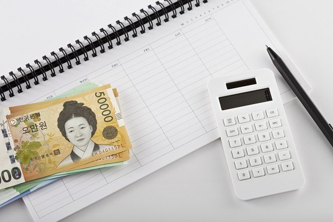 달력 위에 놓인 계산기와 현금 이미지