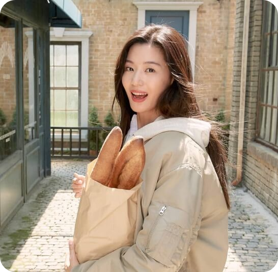 거리에서 빵이 담긴 봉투를 품에 안고 활짝 웃고 있는 배우 전지현의 모습.