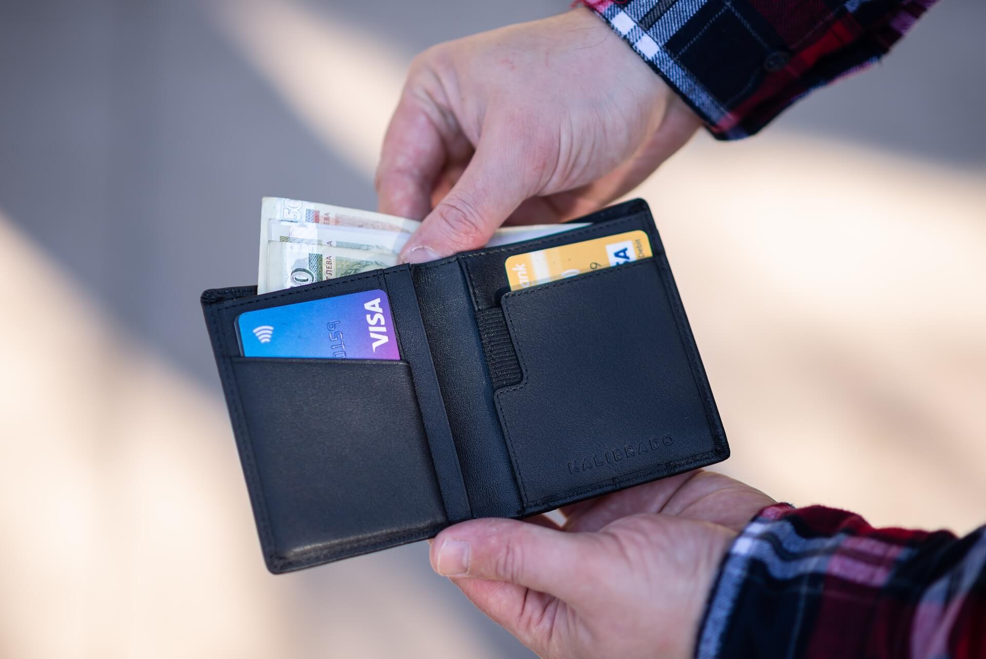 An image of a wallet that contains some dollars and credit cards.