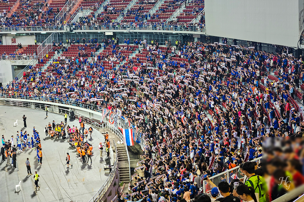 태국 국가대표 선수단을 향해 노래를 부르고 플래카드를 펼쳐 보이는 파란 옷의 태국 응원단