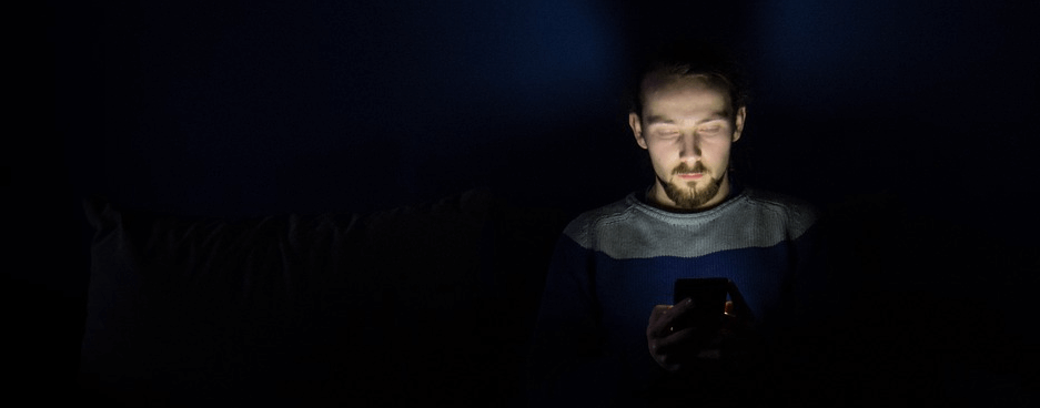 어두운 밤에 남자가 스마트폰을 보고 있다