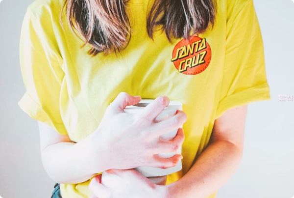 노랑색 티셔츠를 입 은 여자가 화장실 휴지를 끌어안고 있는 모습
