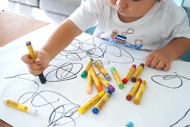 크레파스를 사용하여 도화지 위에 그림을 그리는 중인 아이의 모습