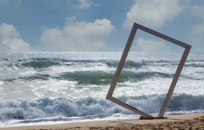 바닷가 백사장 위 창틀 조형물이 기울어져 서있는 이미지