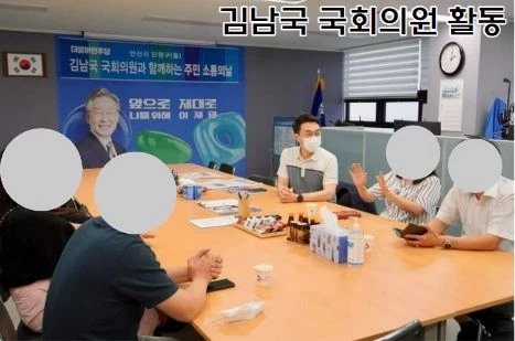 김남국 의원이 과거 활동하던 모습으로 반팔을 입고 테이블에 앉아서 민원인과 이야기를 나누고 있음