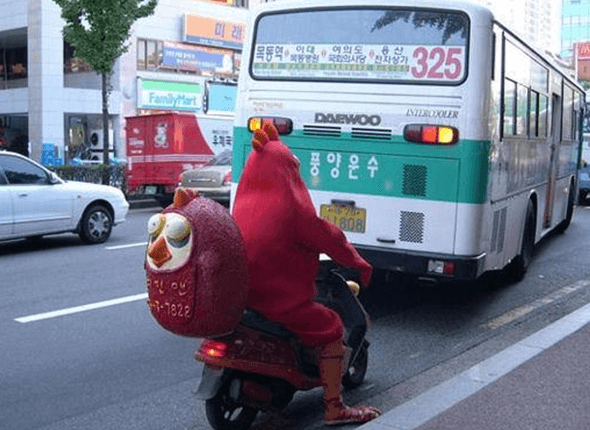 빨간색 닭 코스프레를 하고 오토바이 배달을 하는 배달부