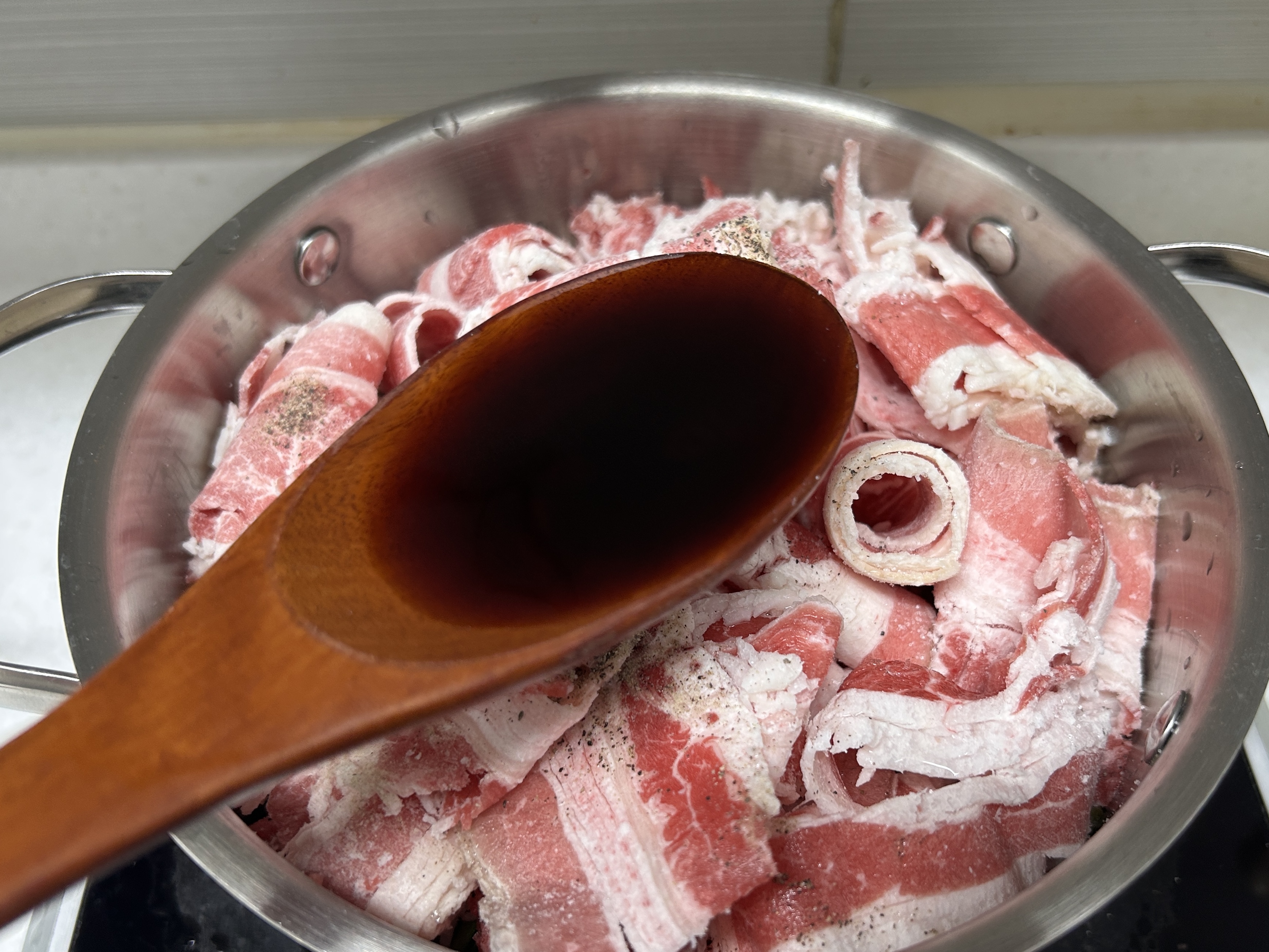 쯔유로 한 숟갈 가득 채운 주걱 뒤로 우삼겹이 든 냄비가 보인다.