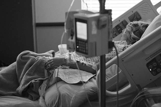 병원-입원실에-환자복을-입은-여자가-병원-침대에-비스듬히-누워-기계에-둘러싸여-있는-모습