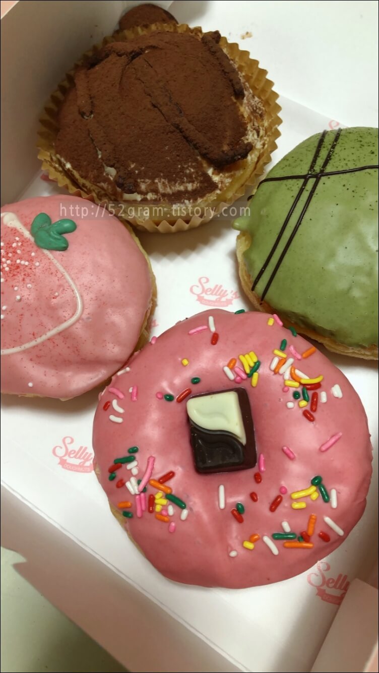 네 가지 도넛이 분홍색 상자에 담겨있다.