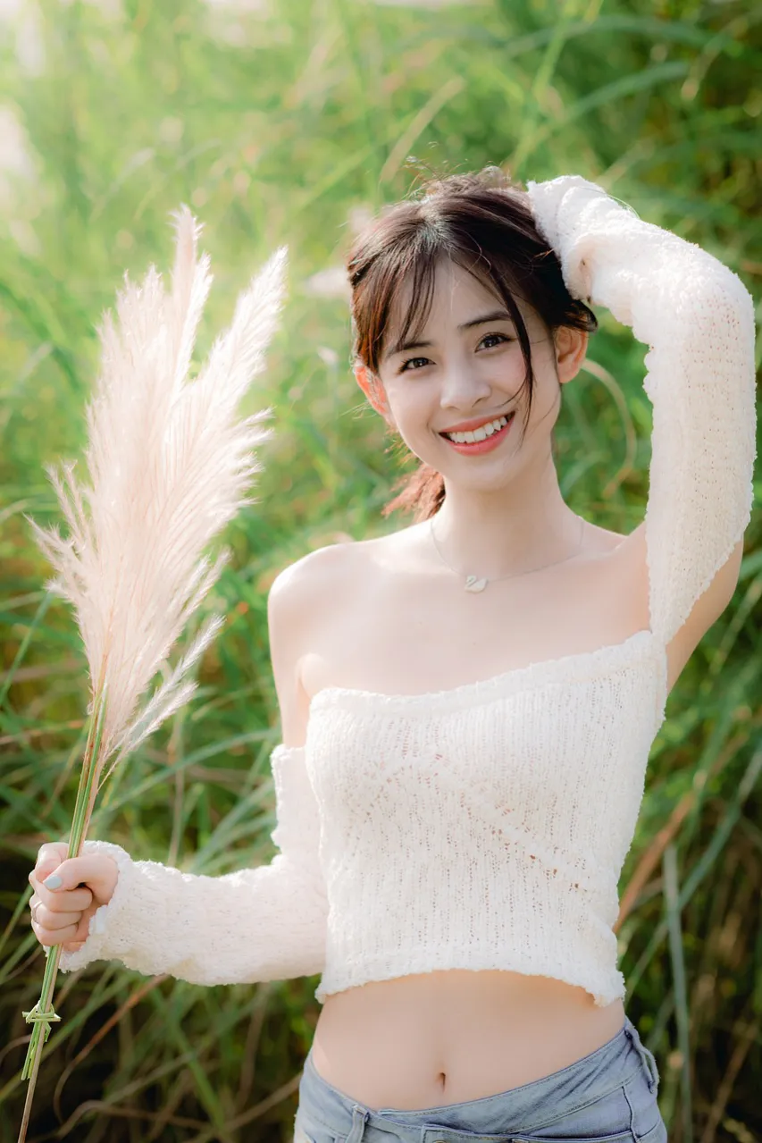 미소가 아름다운 베트남 여성이 풀숲에서 활짝 웃고 있다.