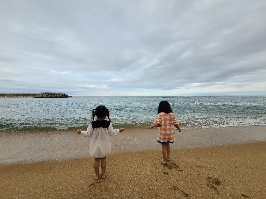 두 아이들이 등대해수욕장 모래사장에 서 있는 모습