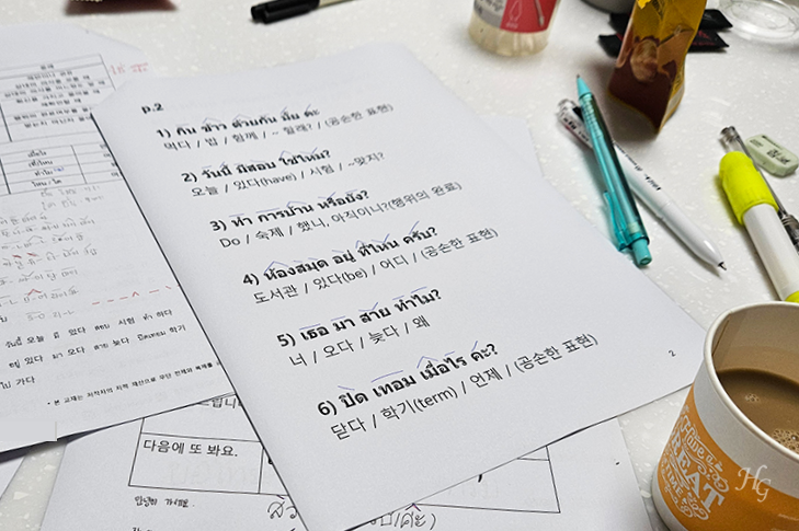 테이블 위에 올라가있는 태국어 학습 프린트와 믹스커피