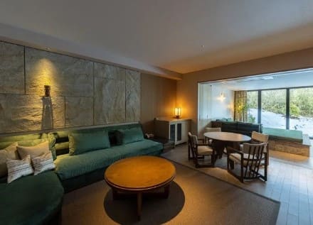 넓은 객실의 사진 초록색 소파와 나무로 만든 의자와 테이블이 보인다.