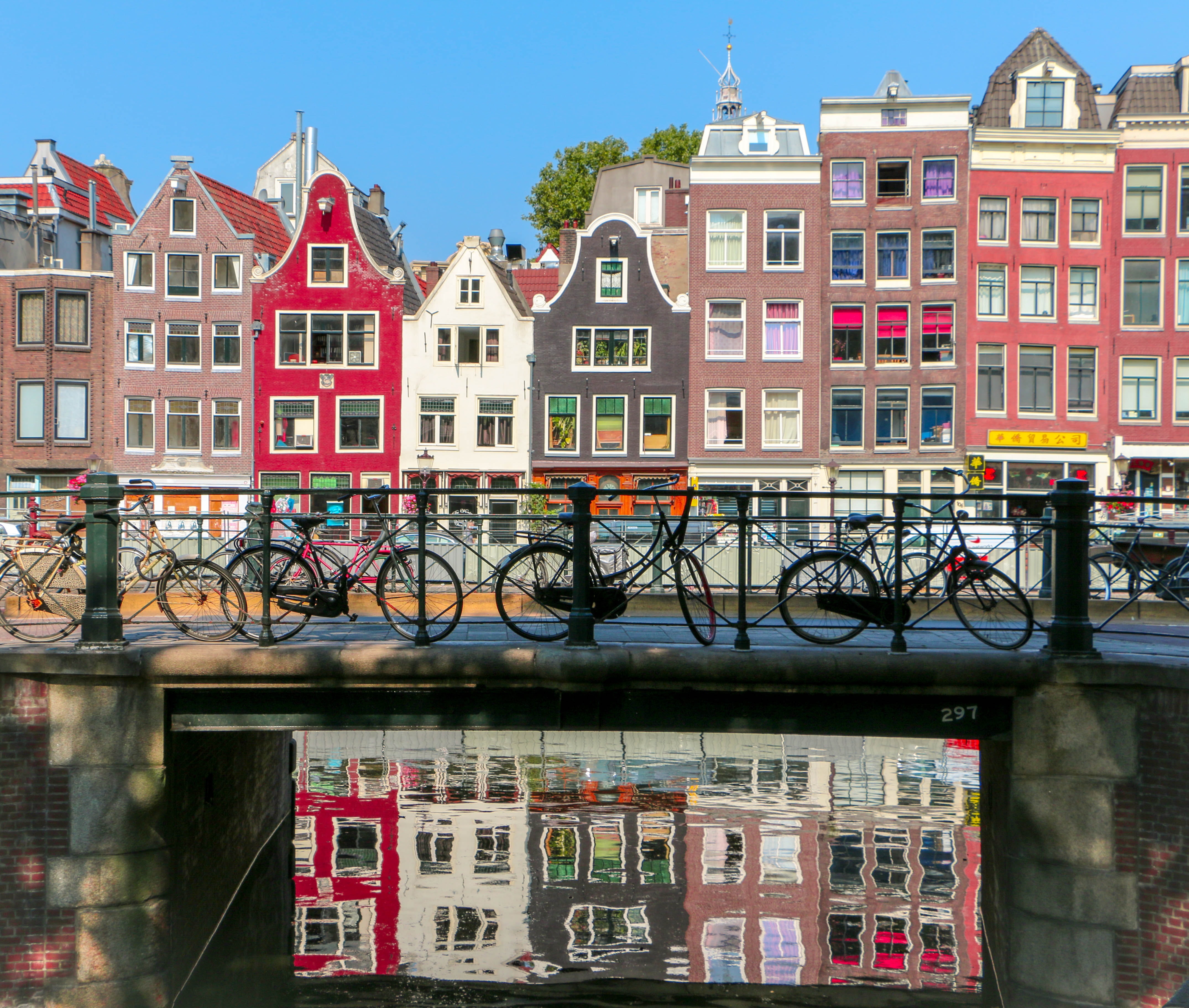 암스테르담 다리에 놓인 자전거들과 그 뒤로 보이는 건물들