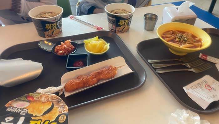 식당의 테이블에 컵라면과 떡뽁이 그리고 순살 닭꼬치가 올려져 있는 사진