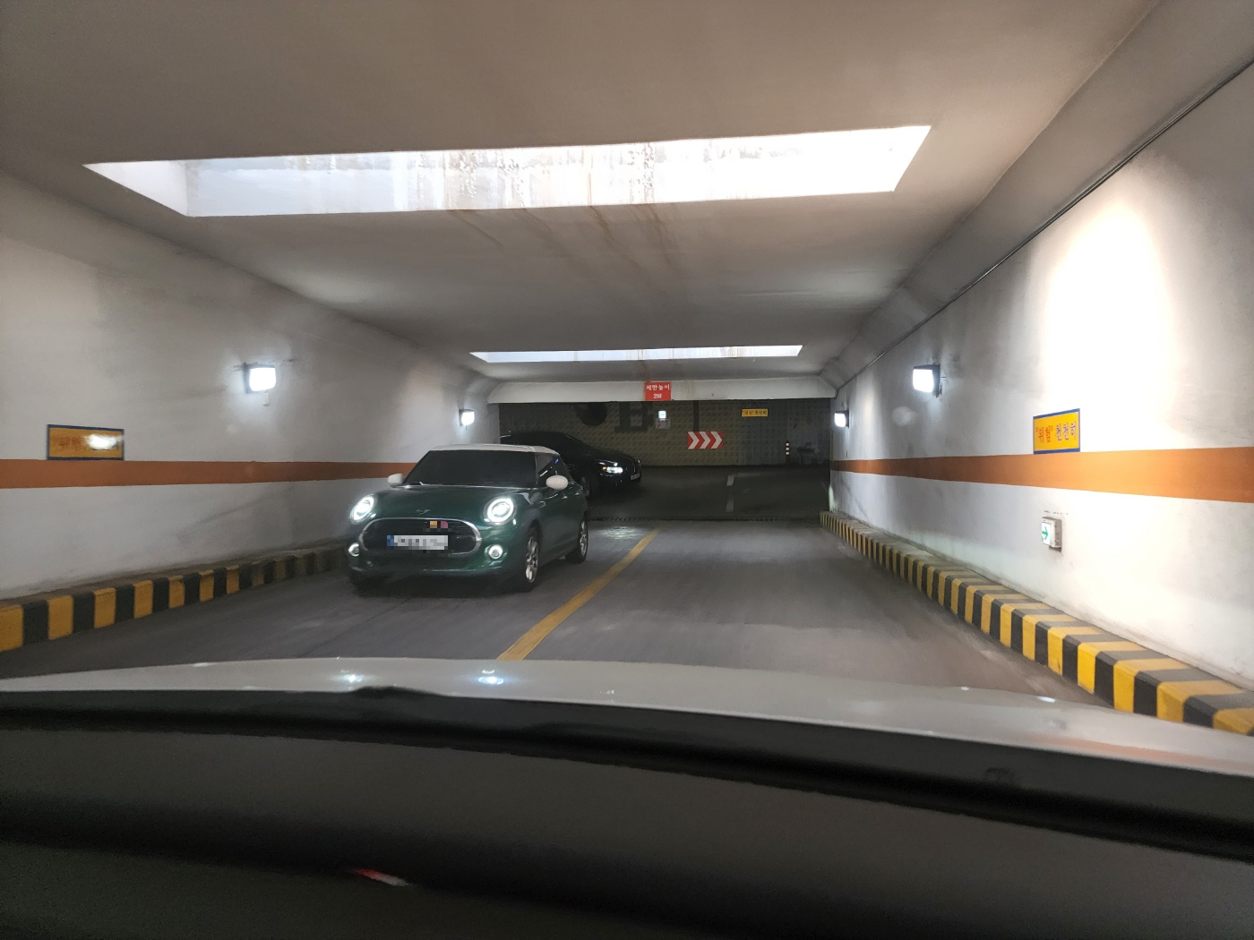 주차장으로 들어가는 터널과 출차하려고 올라오는 초록색 자동차 