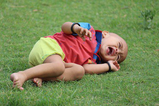 한 두살 배기 아기가 잔디밭에 혼자 누워 울고 있는 사진