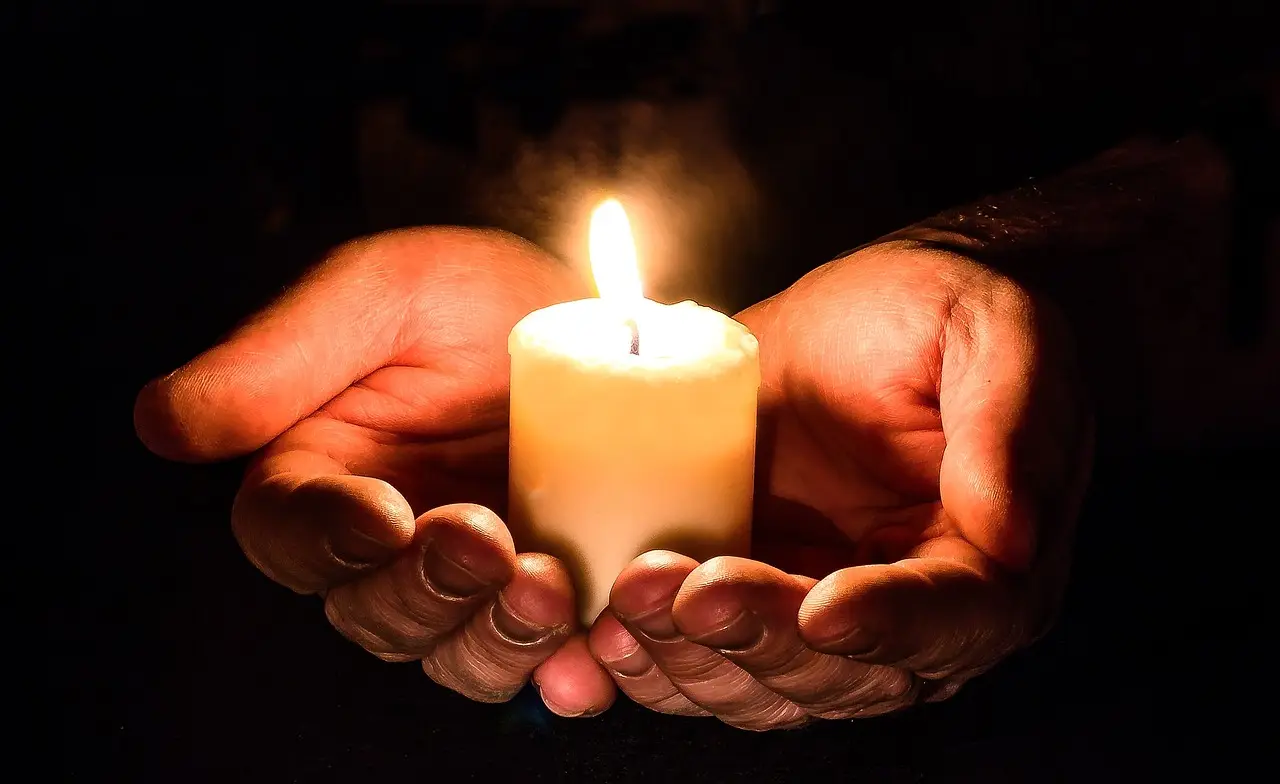 소상공인- 검은배경 두손으로 불이 켜진 촛불을 들고있는 모습