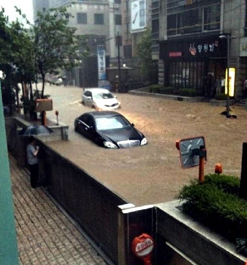 차수문이 가운데에 있고 도로로는 물이 흐르고 주차장쪽은 물이 안들어오는 사진입니다.