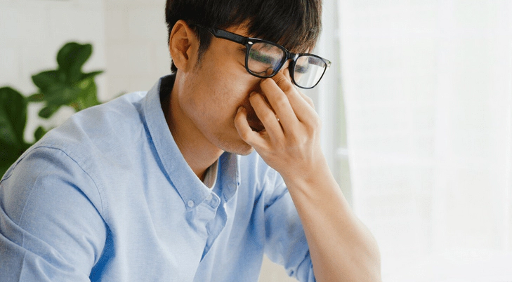 안경쓴 남자가 눈을 비비는 사진