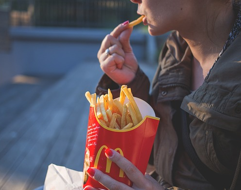 A woman is eating McDonald&#39;s French fries.