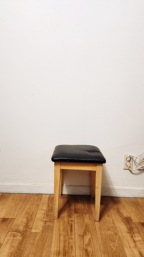 루나군 방에서 여권사진 찍기 준비 하얀 벽지가있는곳에 등받이가 없는 의자를 놓아둠