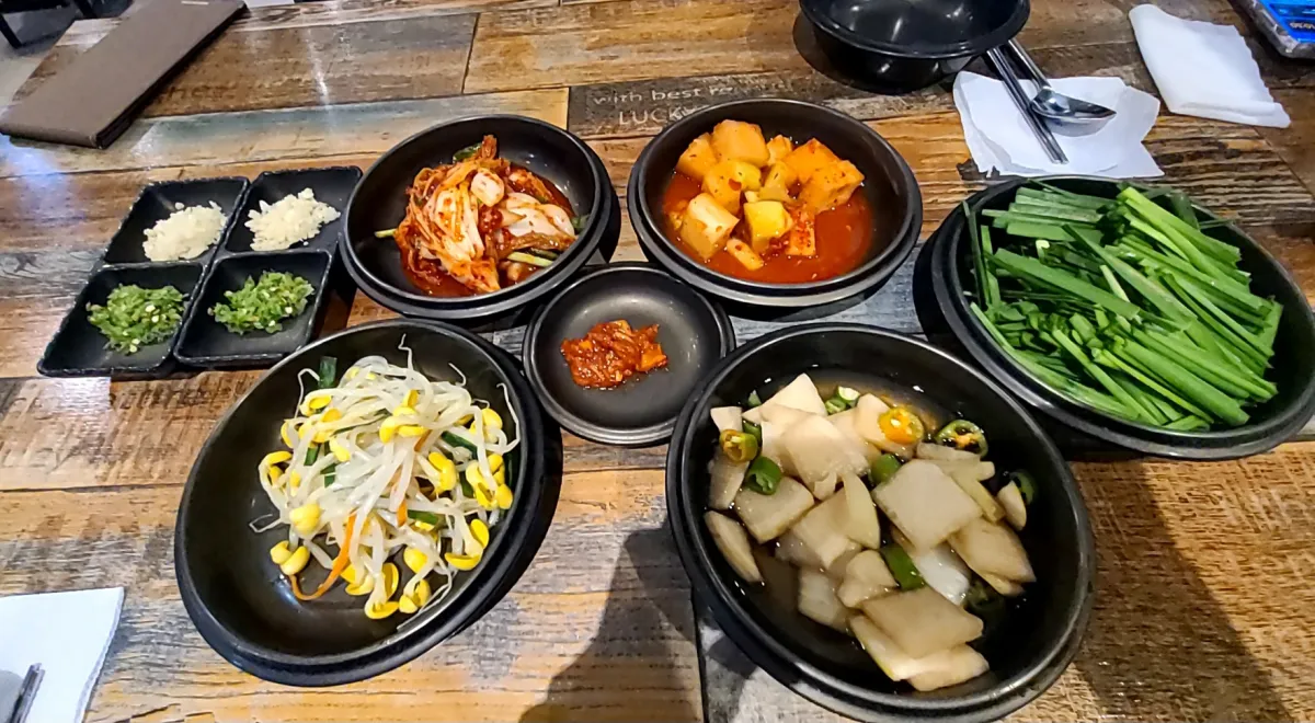 테이블위에-밑반찬-깍두기-배추김치-콩나물무침-양파장아치-부추-마늘-청양고추