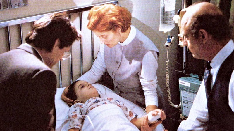 병원 침대에 누워 있는 로렌조와 그를 돌보는 부모