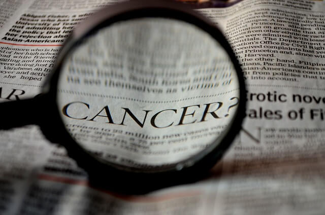 신문에 cancer라는 단어를 돋보기로 확대해놓은 장면