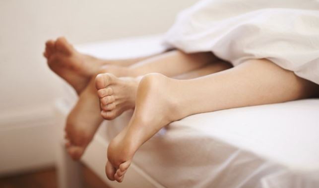 커플이-같은-침대에서-발을-내놓고-있는-사진
