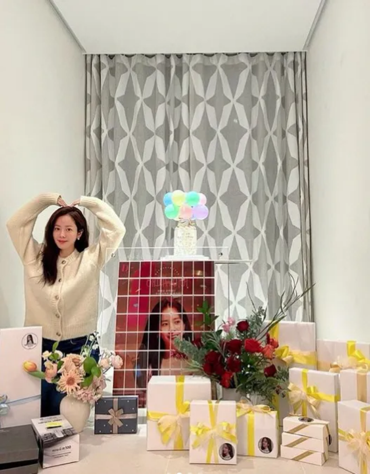 한지민이 팬들에게 받은 선물을 놓고 왼쪽에서 팔을 들어 큰 하트를 하고 있는 모습