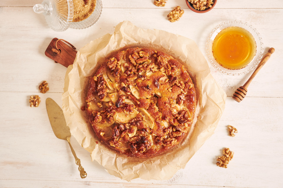 top-view-delicious-apple-walnut-cake-with-honey-surrounded-by-ingredients-white-table-900
