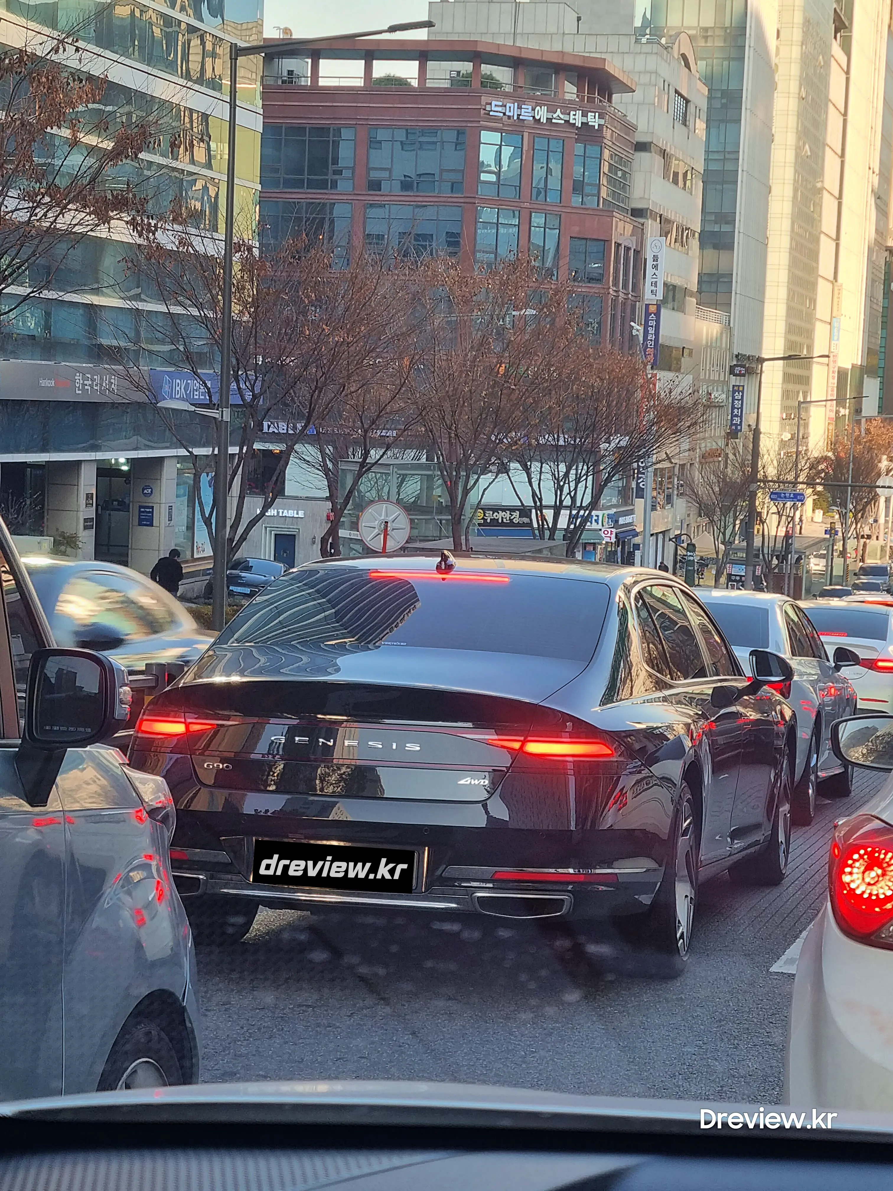 도로위에 차량정체로 멈춰서있는 검정색 제네시스 g90 2023 모델 뒷모습. 